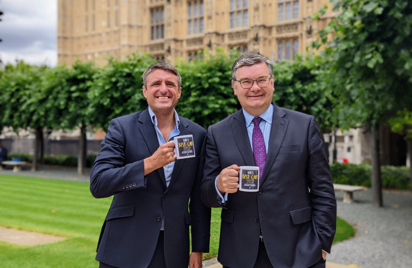 Ben and Iain holding MK's Best Cafe mugs outside the Houses Of Parliament