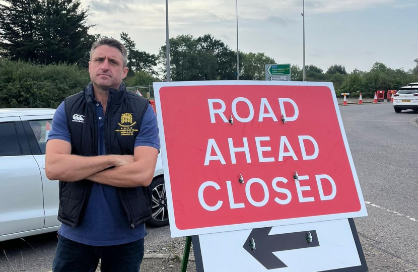 Ben Everitt MP standing next to the 'Road Ahead Closed' sign by the A509 at Newport Pagnell
