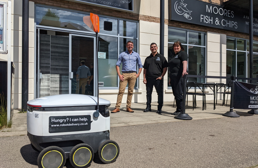 Ben at Moores Fish and Chips with a delivery robot arriving
