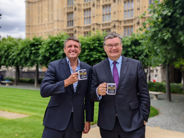 Ben and Iain holding MK's Best Cafe mugs outside the Houses Of Parliament